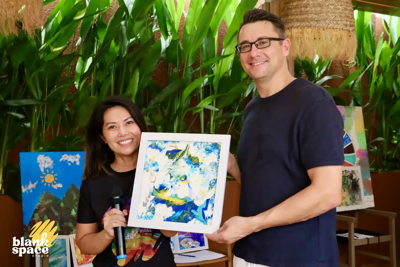 Guest holding a framed blue and green artwork won at the charity auction