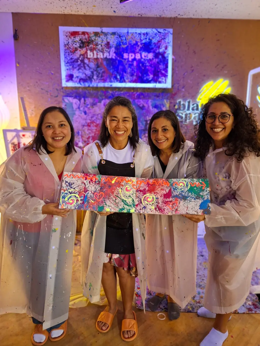 Group of friends holding their collaborative canvas at a ladies night in Saigon