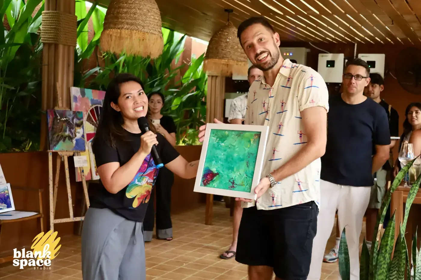 Winning bidder receiving a framed fluid art piece at the charity auction
