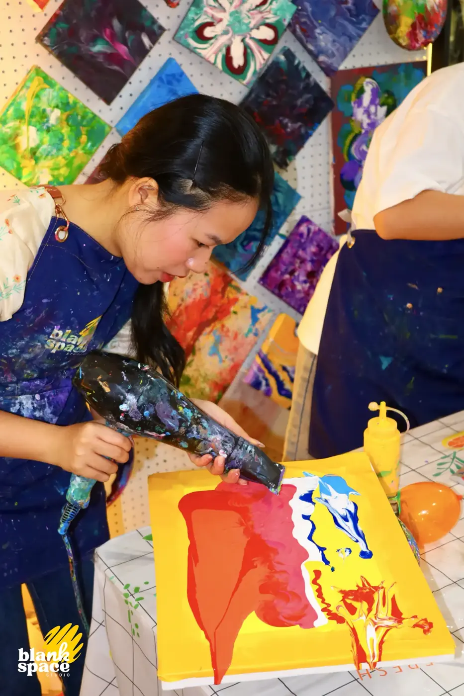 Guest using a heat gun on fluid art at a sip and paint evening in Ho Chi Minh City