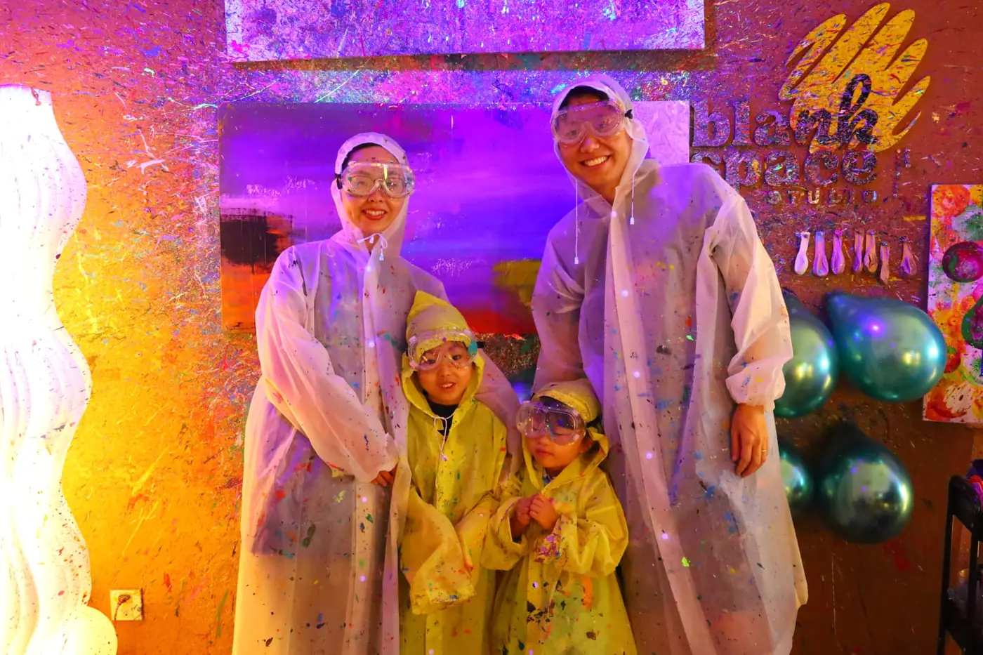 Family in ponchos and goggles after a paint splatter family session in Saigon
