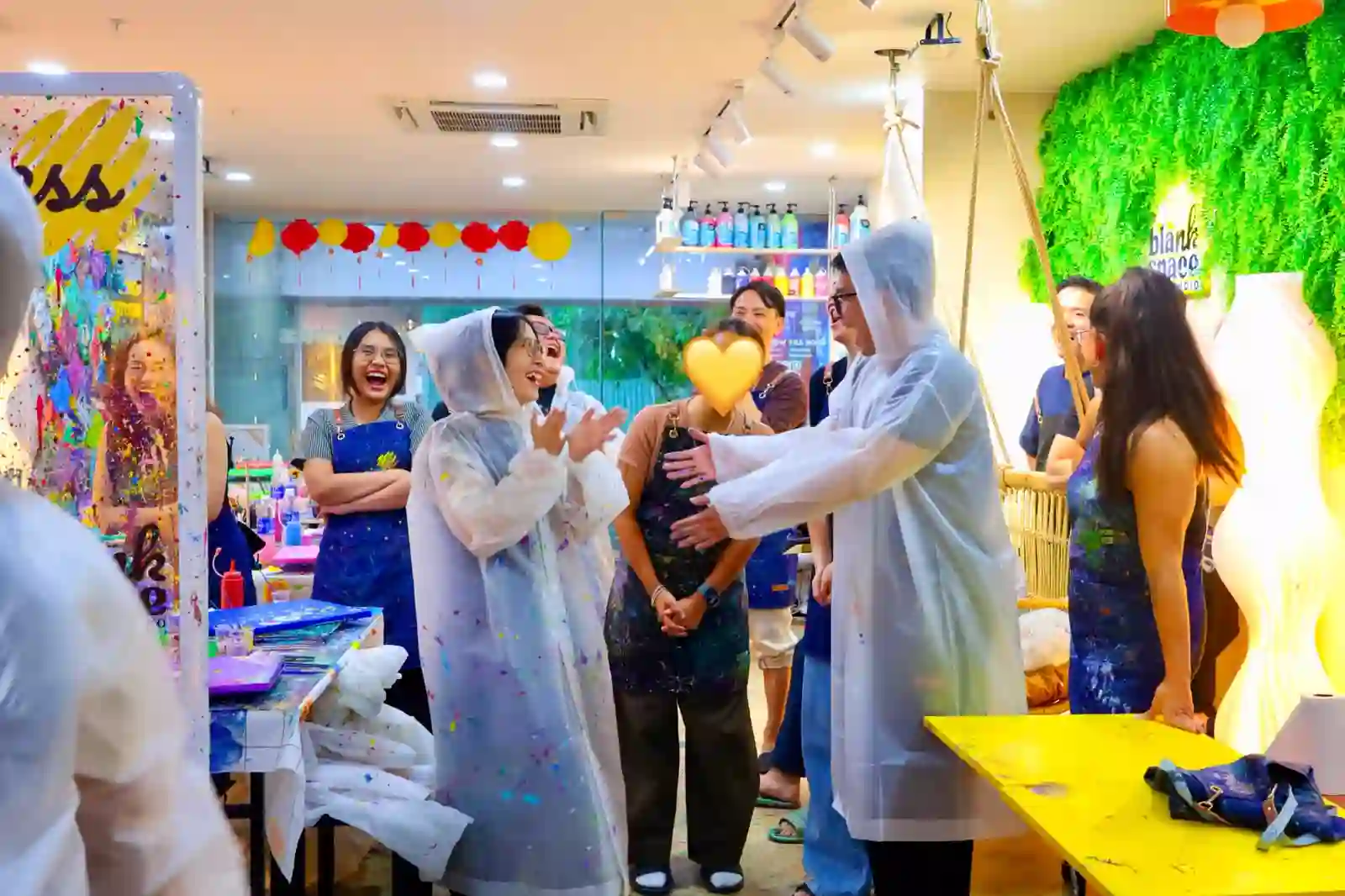Colleagues playing a team game in paint ponchos at Blank Space Studio Saigon