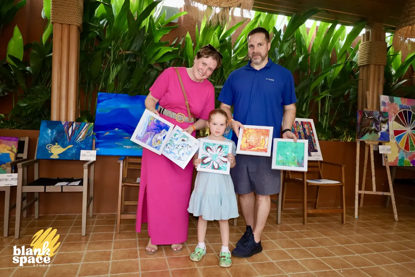 Family holding framed fluid art paintings at the charity art auction in Saigon
