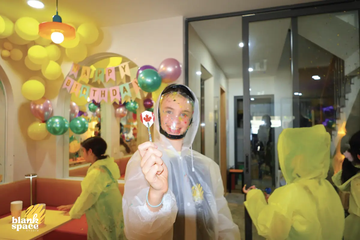 Child in paint poncho with balloons at a birthday venue near Thao Dien