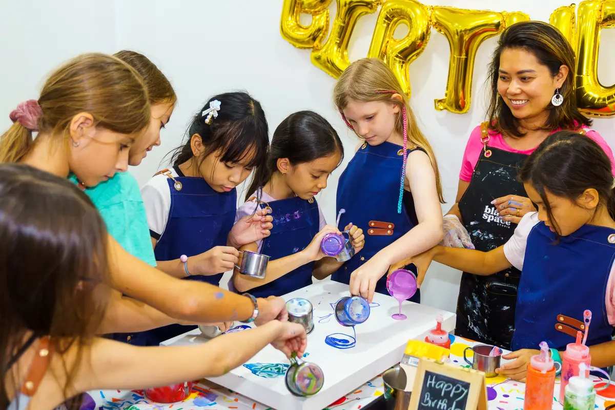 Kids pouring paint together at a creative birthday party in Saigon