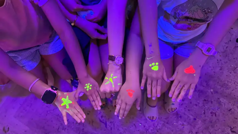 Kids showing glow in the dark paint designs on their hands
