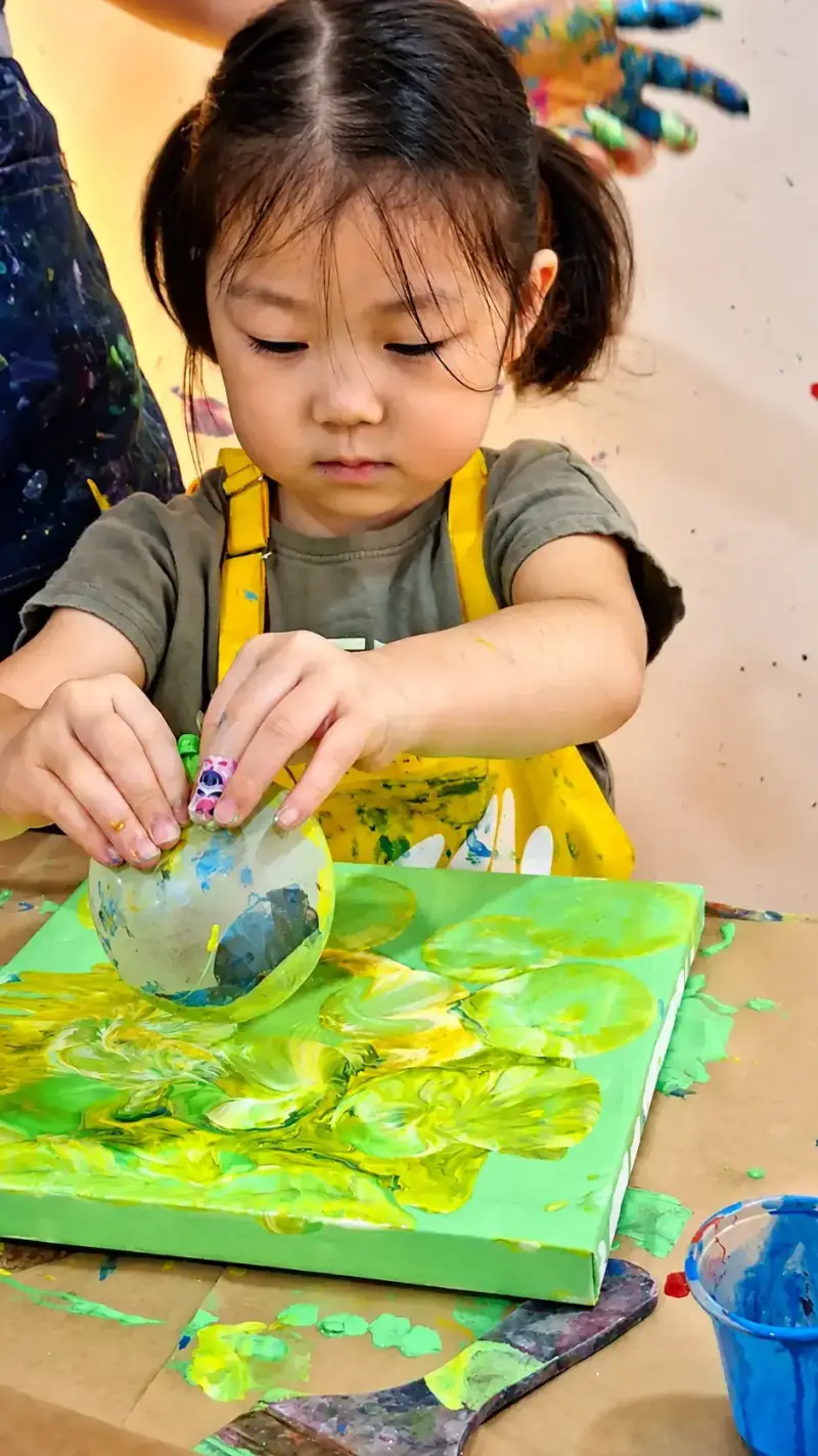 Preschooler doing balloon paint printing at art camp near Thao Dien