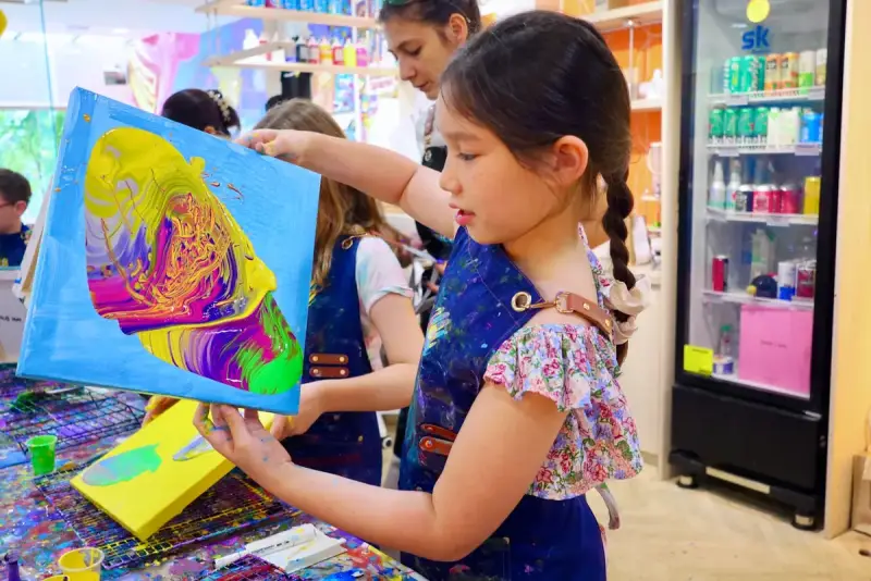 Girl holding her fluid art canvas at a birthday party near Thao Dien