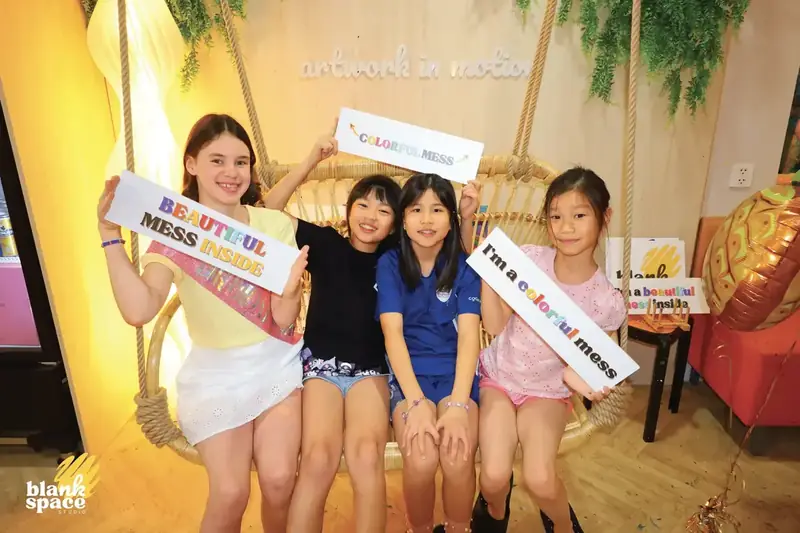 Kids holding colorful signs at a unique birthday party venue in HCMC