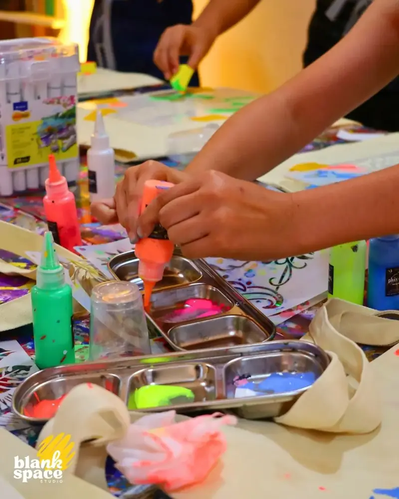 Kids squeezing neon paint at a birthday art workshop near Thao Dien Saigon