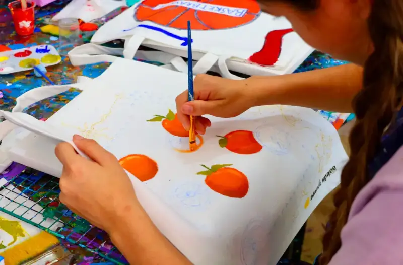 Girl painting a custom tote bag at a kids birthday party in Saigon