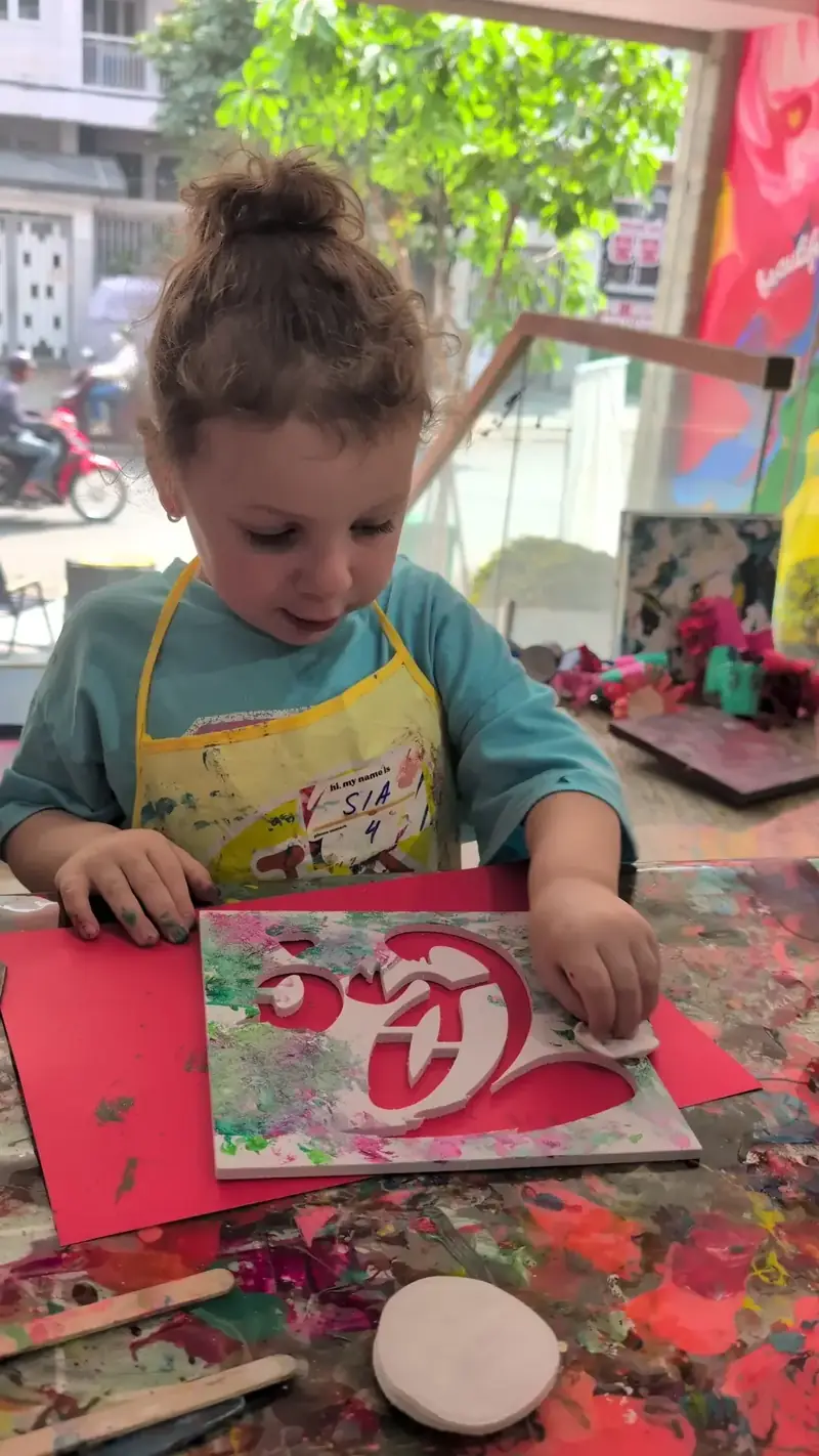 Girl creating stencil art at a holiday activity in Saigon