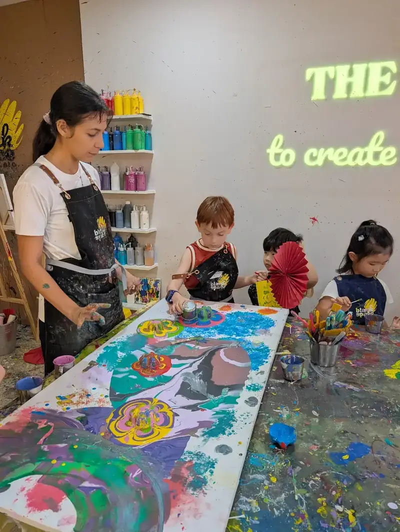 Group pouring paint on large table at a school holiday camp in Saigon