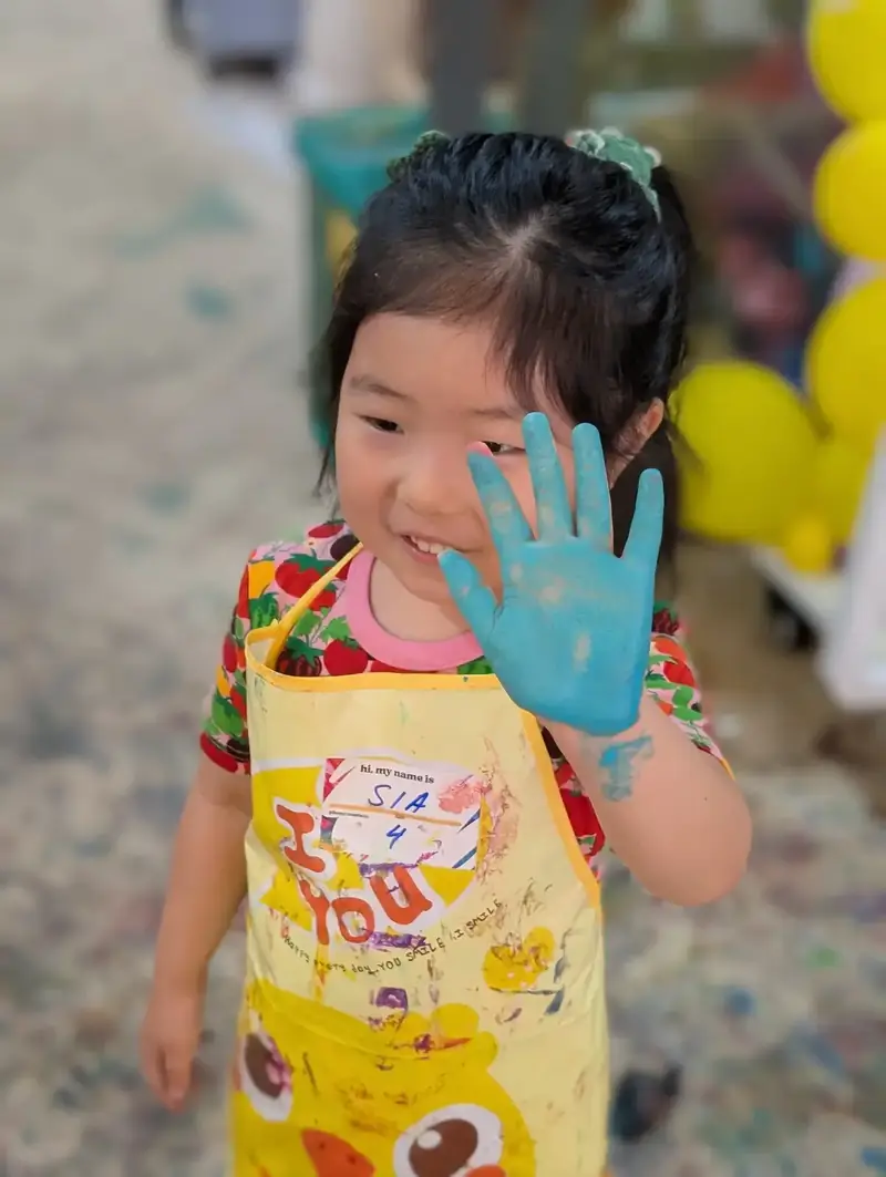 Little girl with blue painted hand at a kids art activity in Ho Chi Minh City
