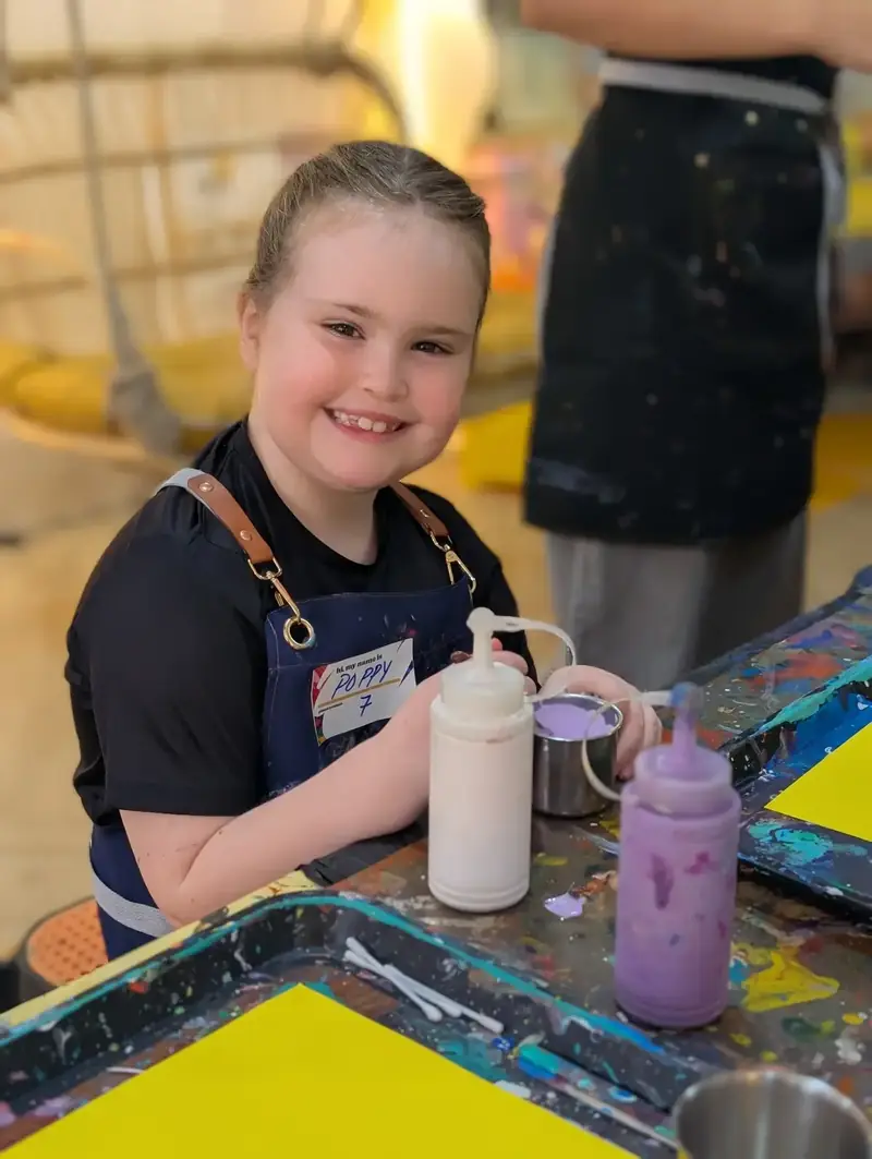 Smiling girl with paint bottles at an after school activity in Saigon