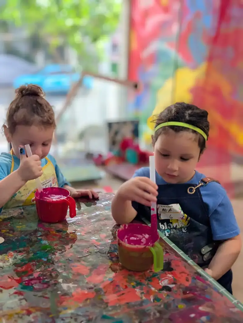 Kids mixing paint in cups at a paint pouring class for kids in Saigon