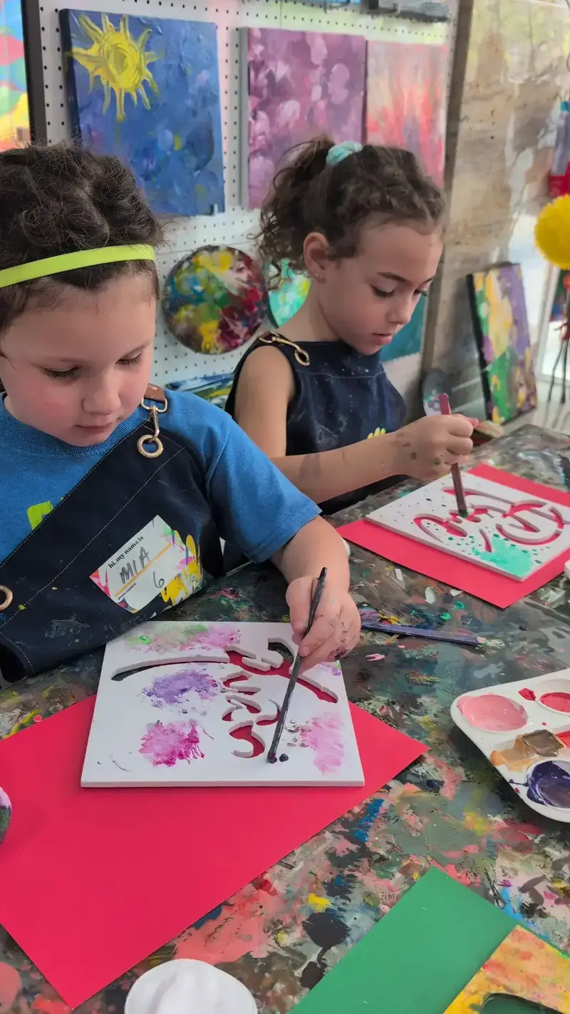 Two girls working on stencil art at an indoor kids activity near Thao Dien