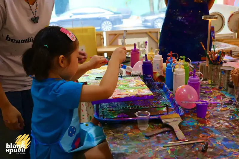 Young child creating a fluid art canvas with her parent in Saigon