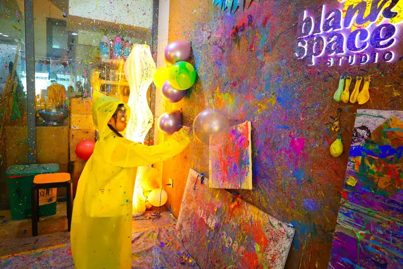 Child throwing darts at paint balloons on the splatter wall in Ho Chi Minh City