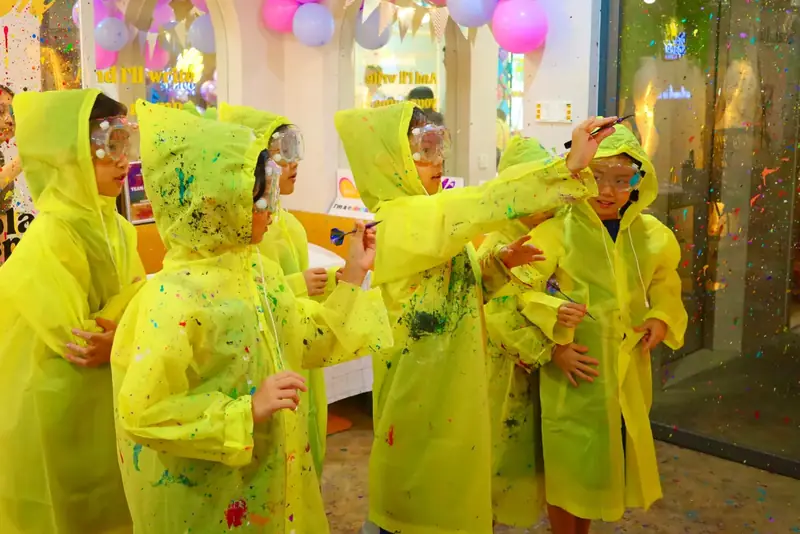 Kids in splatter ponchos throwing paint darts at Blank Space Studio Saigon