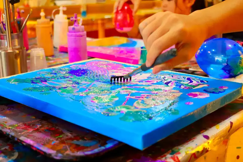 Making textures in wet fluid art paint on a blue canvas