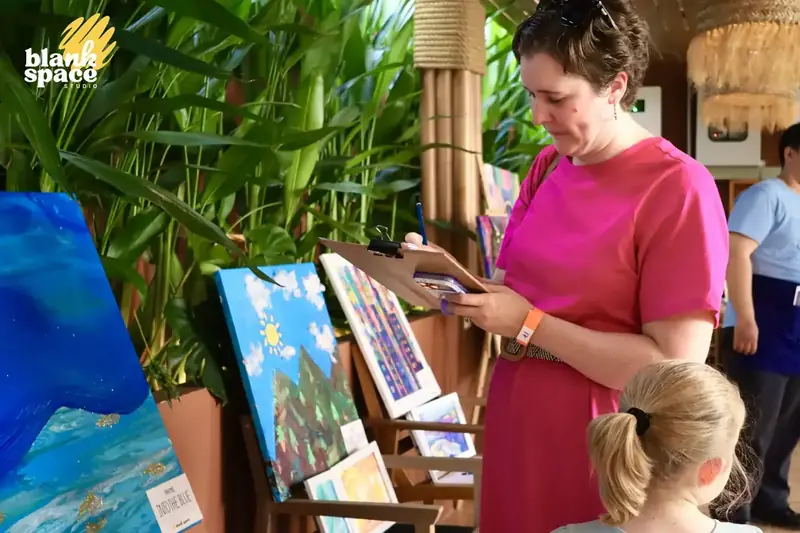 Guest writing a silent auction bid next to a painting in Ho Chi Minh City