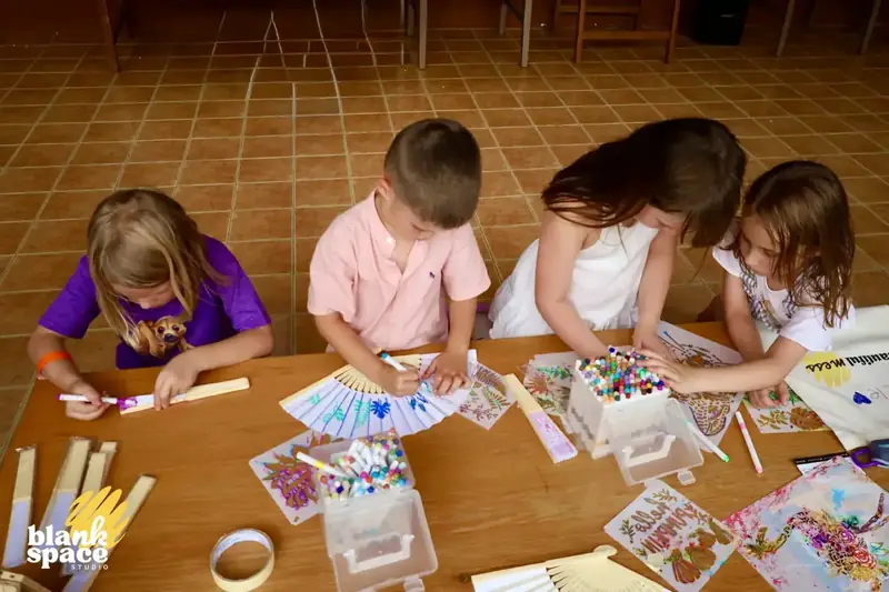 Kids decorating paper fans during the charity art auction event