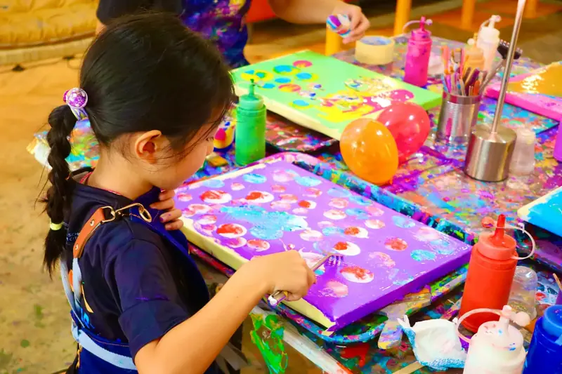 Girl painting colorful dots on a purple canvas at a creative celebration