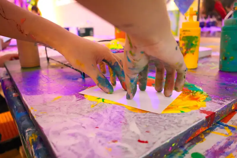 Child pressing paint-covered hands onto paper at a creative party in Ho Chi Minh City