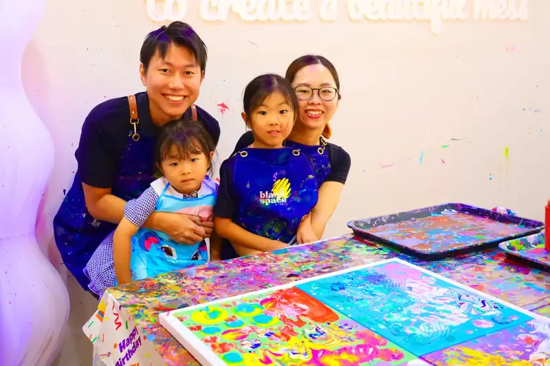 Family posing with their finished fluid art canvases near Thao Dien
