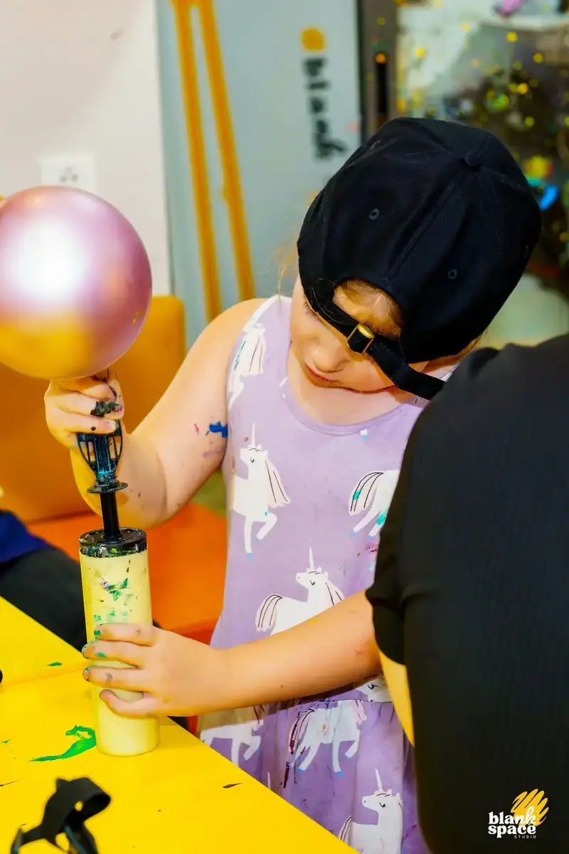 Girl using balloon pump to create art at a birthday party in Saigon