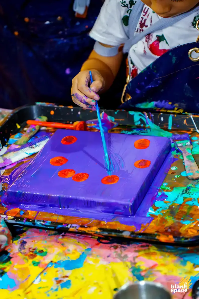 Child painting a purple canvas at an art class for kids near Thao Dien