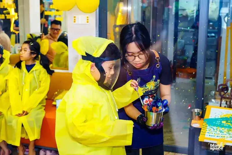 Staff guiding a child through paint pouring at Blank Space Studio Saigon