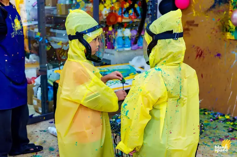 Kids in protective suits enjoying splatter paint at a holiday camp in Saigon