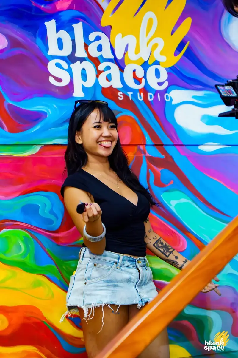 Founder in front of colorful mural at Blank Space Studio Thao Dien