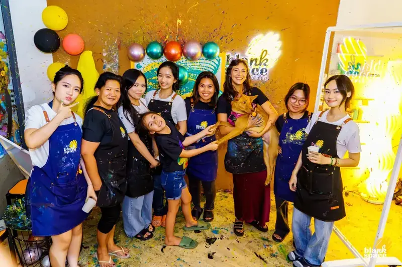 Staff team with studio dog at a sip and paint evening in HCMC