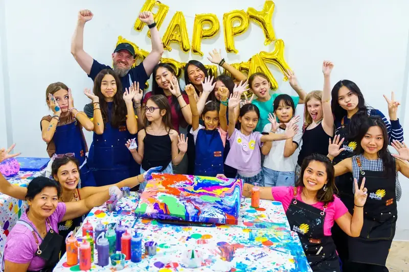 Group photo from a paint pouring celebration at Blank Space Studio HCMC