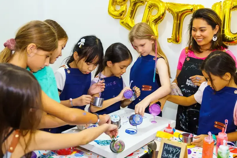 Kids pouring paint together at a creative birthday party in Saigon