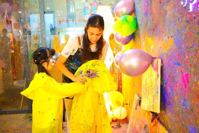 Friendly studio guide helping a child with splatter painting at a private event