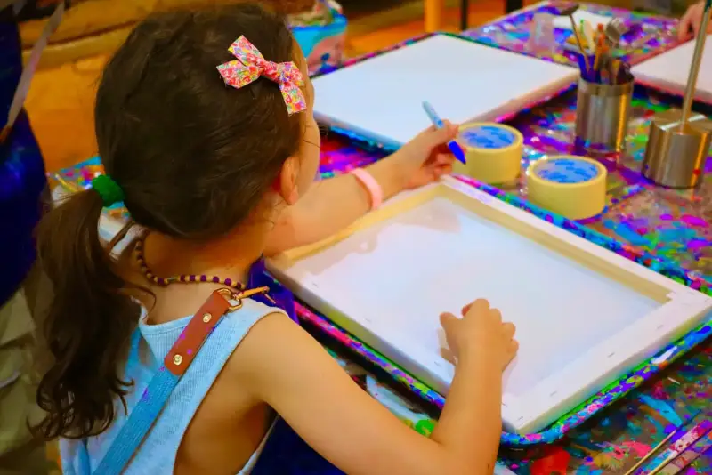 Child preparing a canvas to take home after a private studio session in Ho Chi Minh City