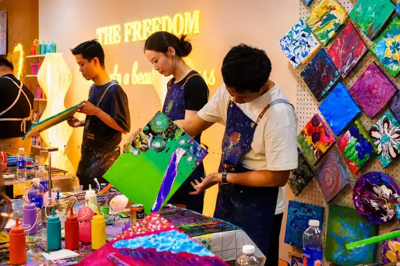Friends painting canvases at a sip and paint night in Saigon