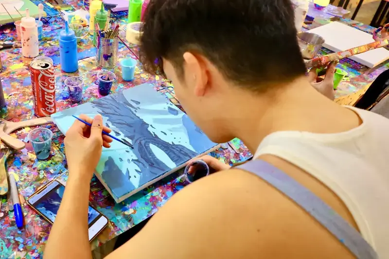 Guest painting a blue canvas at a sip and paint evening in Ho Chi Minh City