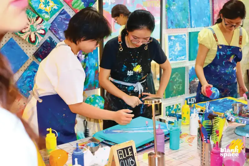 Team bonding guests creating fluid art together at Blank Space Studio