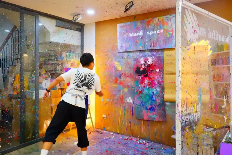 Team member throwing paint at a giant company canvas during a team bonding event in Ho Chi Minh City