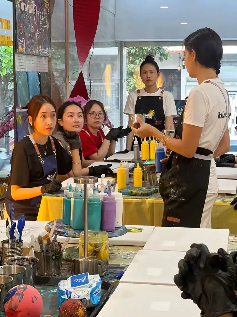 Staff guiding a creative team building paint session in Saigon