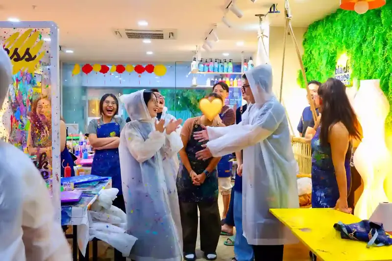 Colleagues playing a team game in paint ponchos at Blank Space Studio Saigon
