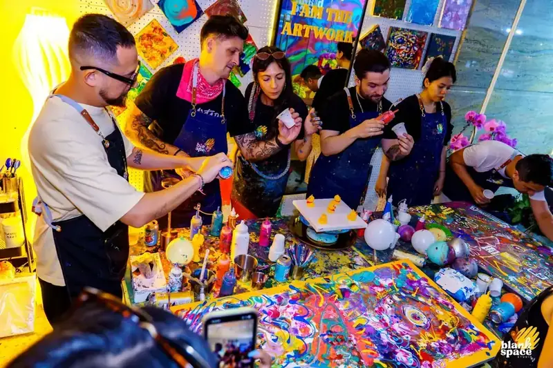 Colleagues pouring paint at a creative team building workshop near Thao Dien